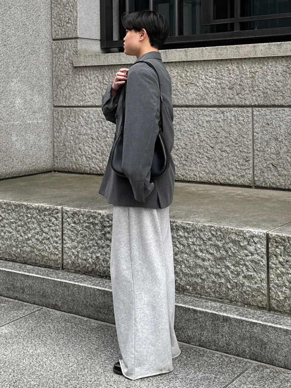 グレー系のテーラードジャケット、ブラック系のショルダーバッグ、グレー系のスウェットパンツを着用したメンズの春コーディネートの3枚目の写真