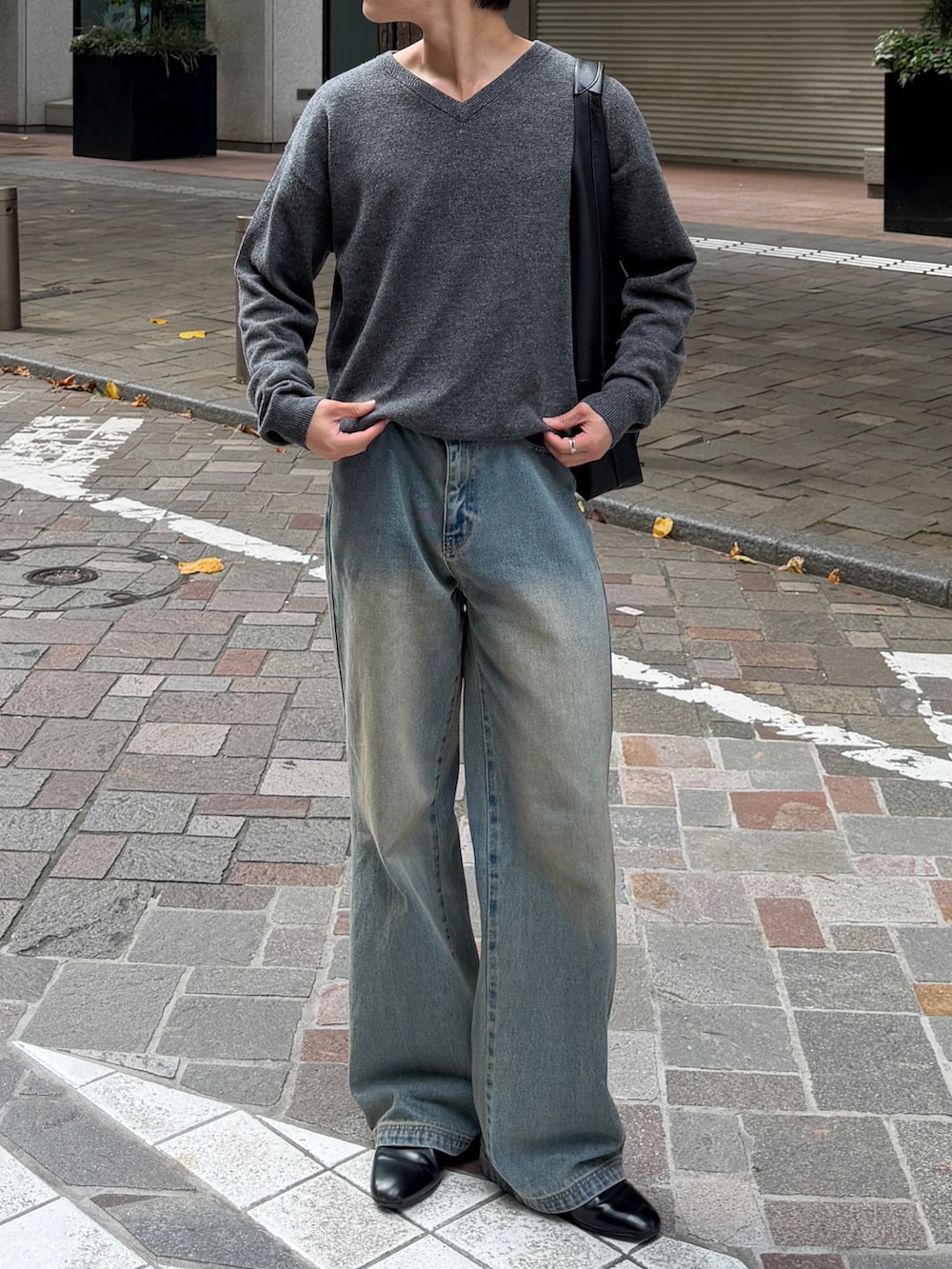 ブルー系のデニムパンツ、ブラック系のドレスシューズ、グレー系のニット/セーターを着用したメンズの秋コーディネートの4枚目の写真