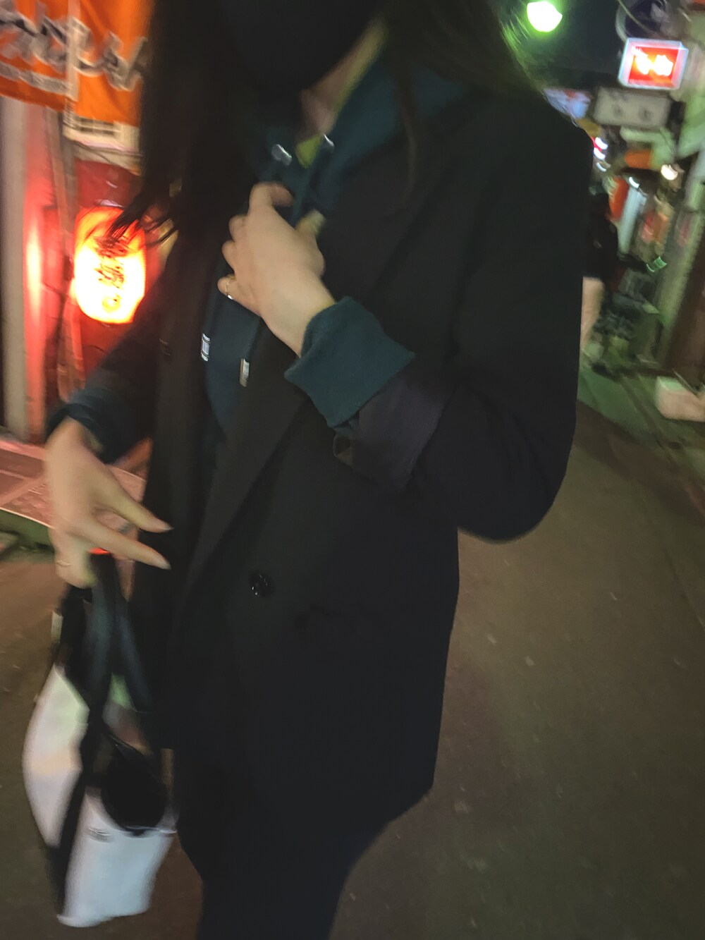 ブラック系のノーカラージャケット、ホワイト系のハンドバッグ、グリーン系のパーカーを着用したレディースの冬コーディネートの2枚目の写真