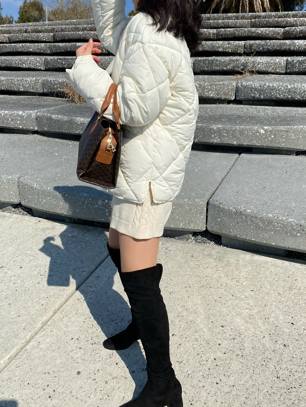 ブラック系のブーツ、ベージュ系のパンツ、ホワイト系のジャケット/アウターを着用したレディースの冬コーディネートの3枚目の写真