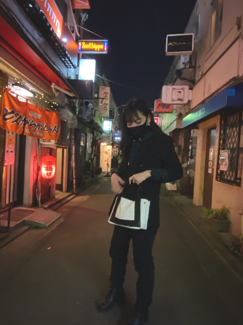 ブラック系のノーカラージャケット、ホワイト系のハンドバッグ、グリーン系のパーカーを着用したレディースの冬コーディネートの3枚目の写真