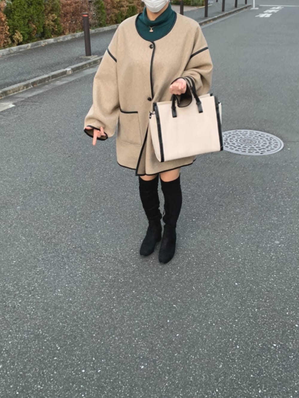 ホワイト系のハンドバッグ、ベージュ系のその他アウター、グリーン系のニット/セーターを着用したレディースの冬コーディネートの2枚目の写真