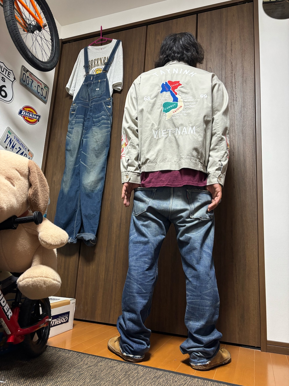 グレー系のスカジャン、レッド系のTシャツ/カットソー、ブルー系のデニムパンツを着用したメンズの夏コーディネートの2枚目の写真