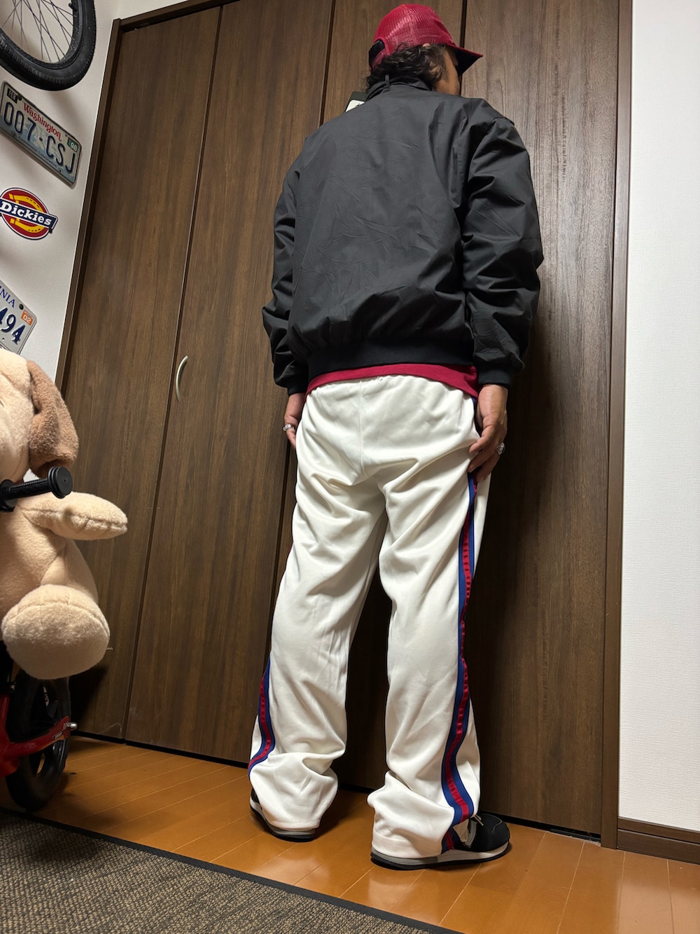 ブラック系のミリタリージャケット、ホワイト系のスウェットパンツ、ブラック系のスニーカーを着用したメンズの夏コーディネートの2枚目の写真