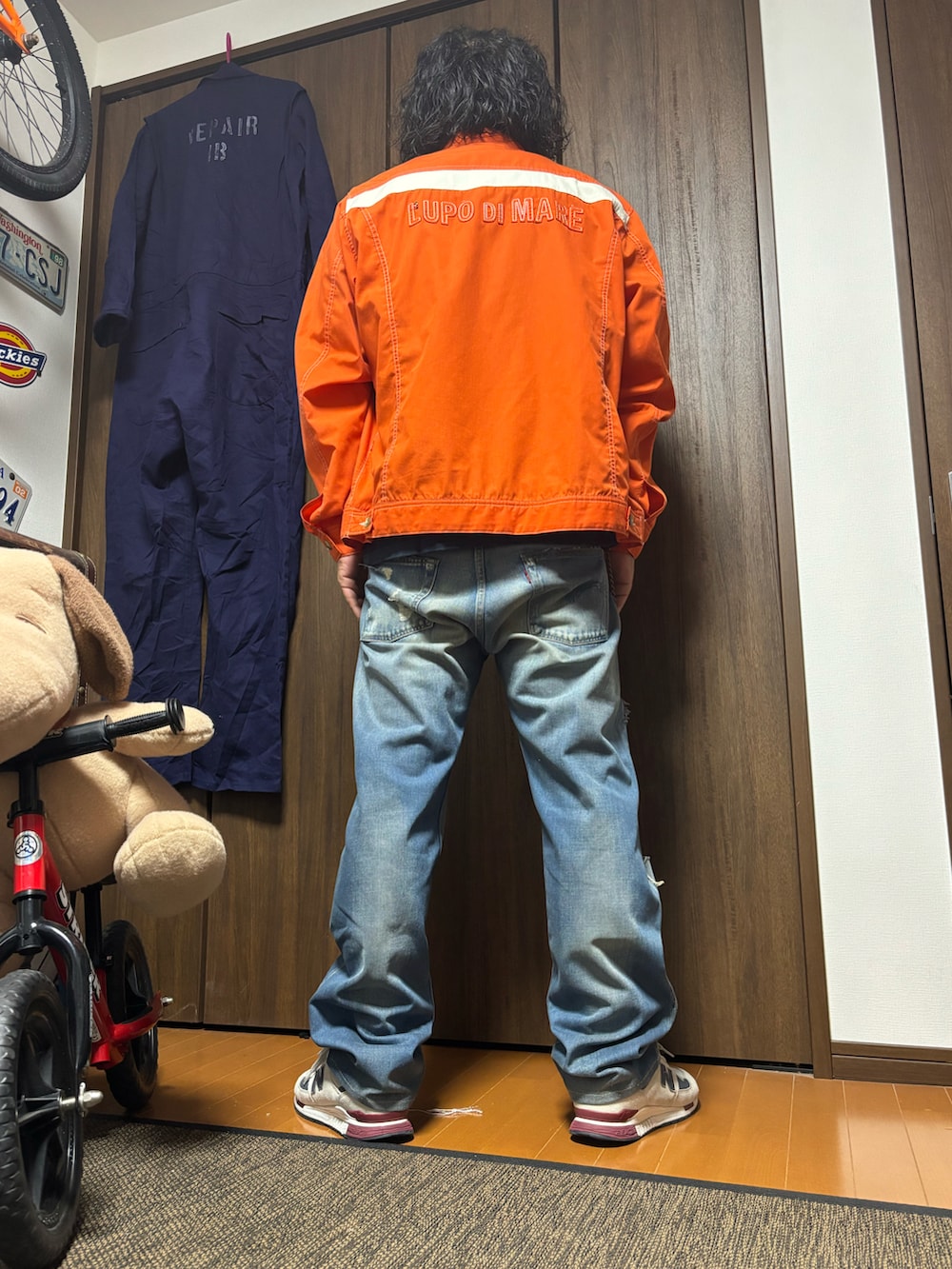 ブラック系のTシャツ/カットソー、オレンジ系のノーカラージャケット、ブルー系のデニムパンツを着用したメンズの春コーディネートの2枚目の写真
