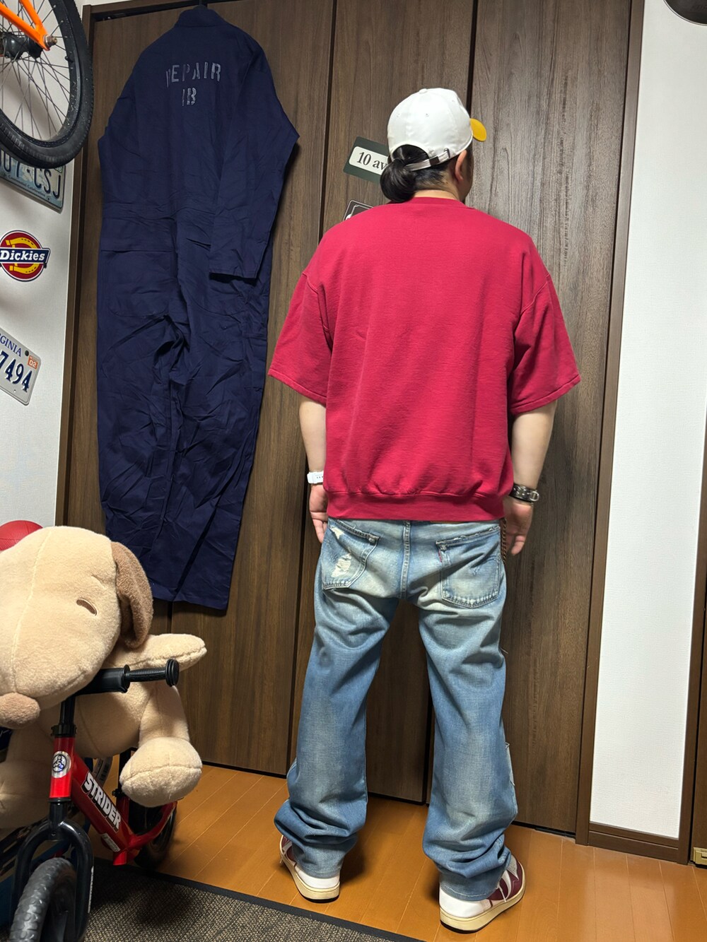 レッド系のTシャツ/カットソー、ブルー系のデニムパンツ、ホワイト系のスニーカーを着用したメンズの春コーディネートの2枚目の写真