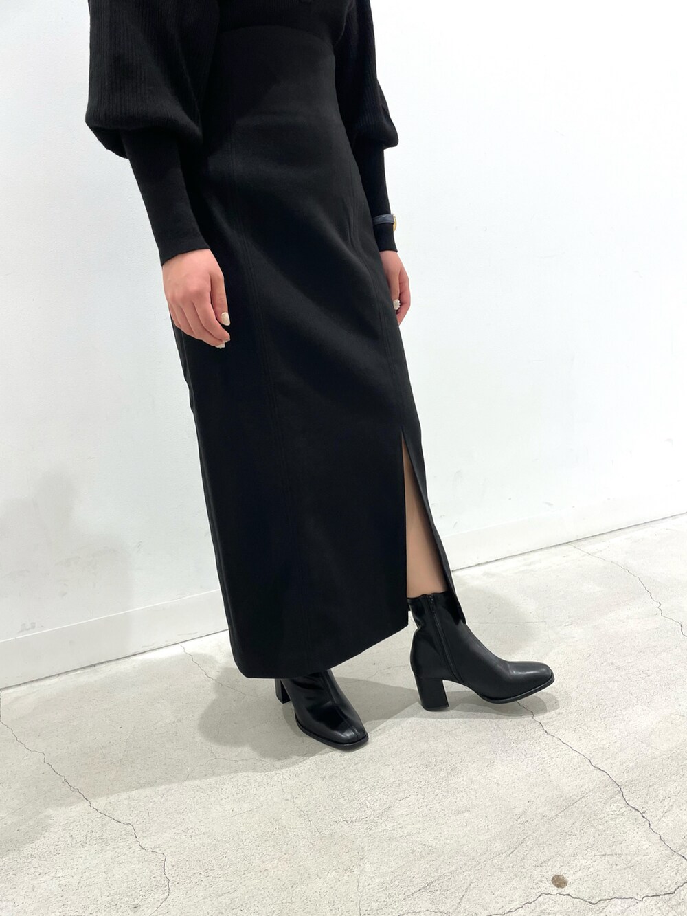 ブラック系のニット/セーター、ブラック系のスカート、ブラック系のブーツを着用したレディースの秋コーディネートの3枚目の写真