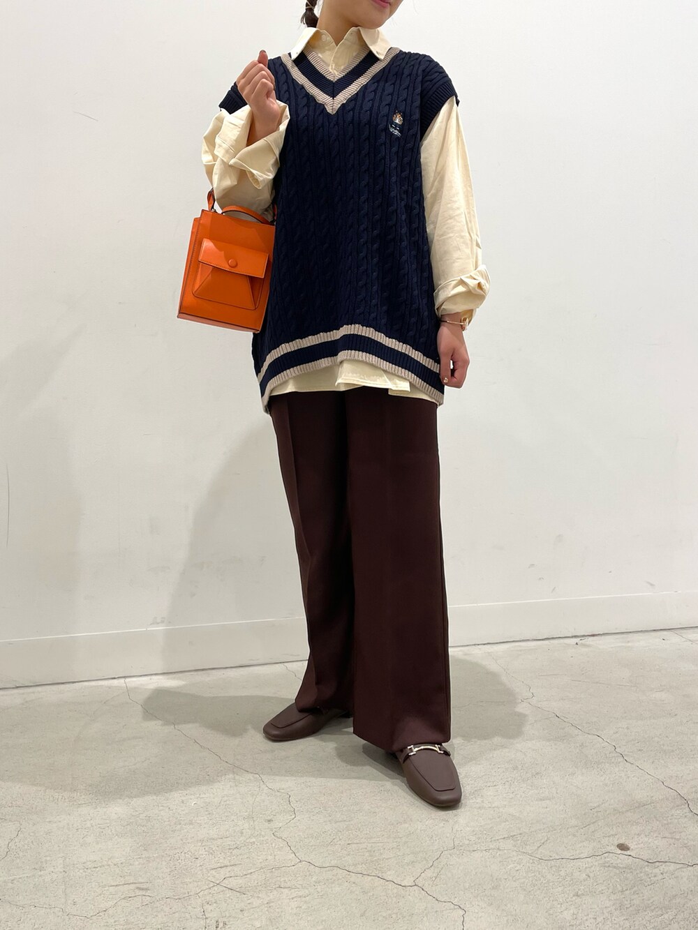 ブルー系のベスト、ベージュ系のシャツ/ブラウス、オレンジ系のショルダーバッグを着用したレディースの夏コーディネートの2枚目の写真