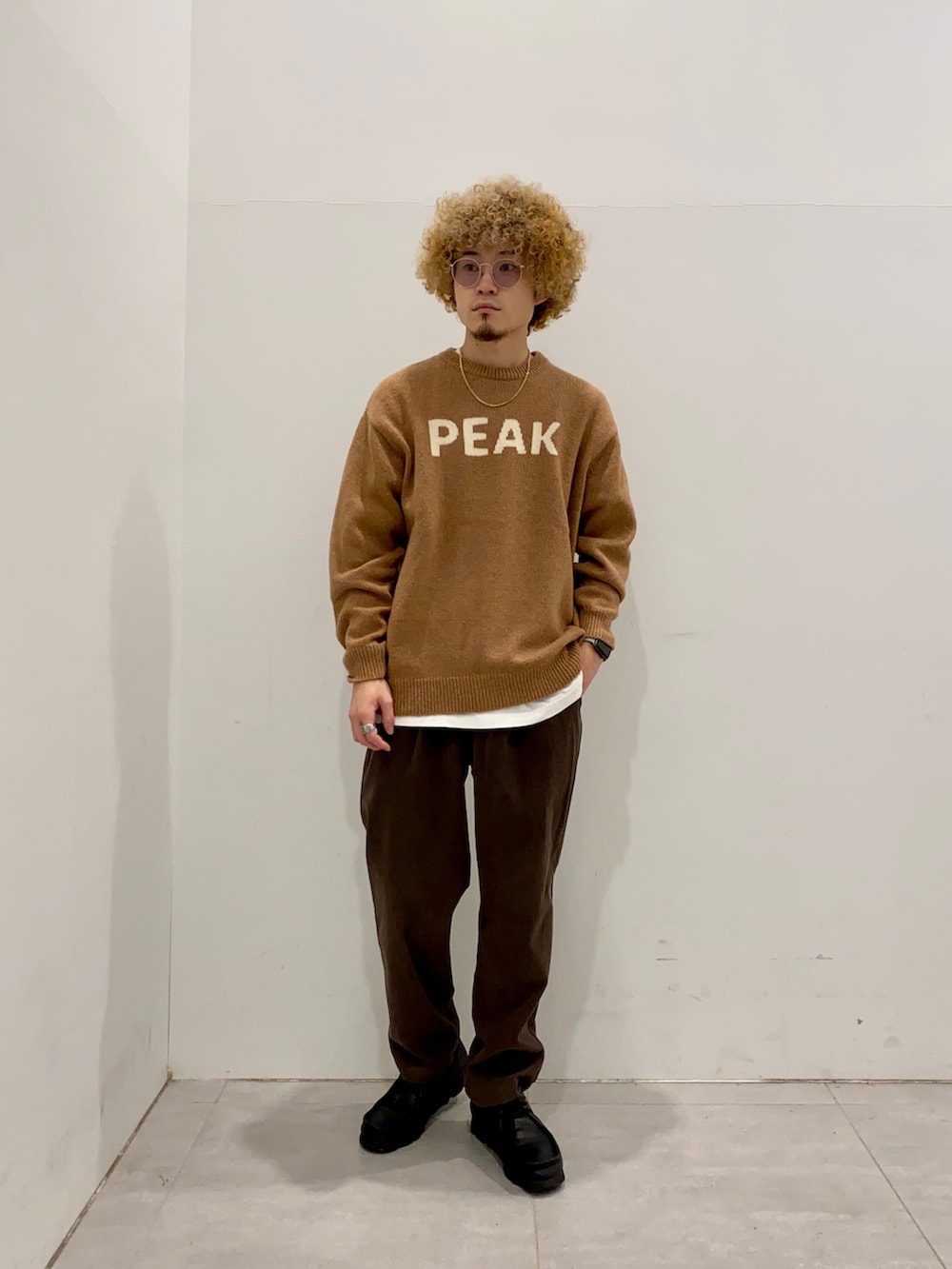 イエロー系のニット/セーター、ブルー系のマウンテンパーカー、ブラウン系のその他パンツを着用したメンズの秋コーディネートの3枚目の写真