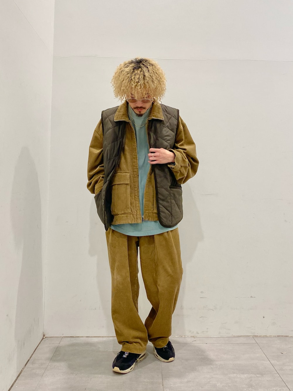 グリーン系のダウンベスト、イエロー系のブルゾン、イエロー系のスラックスを着用したメンズの秋コーディネートの2枚目の写真
