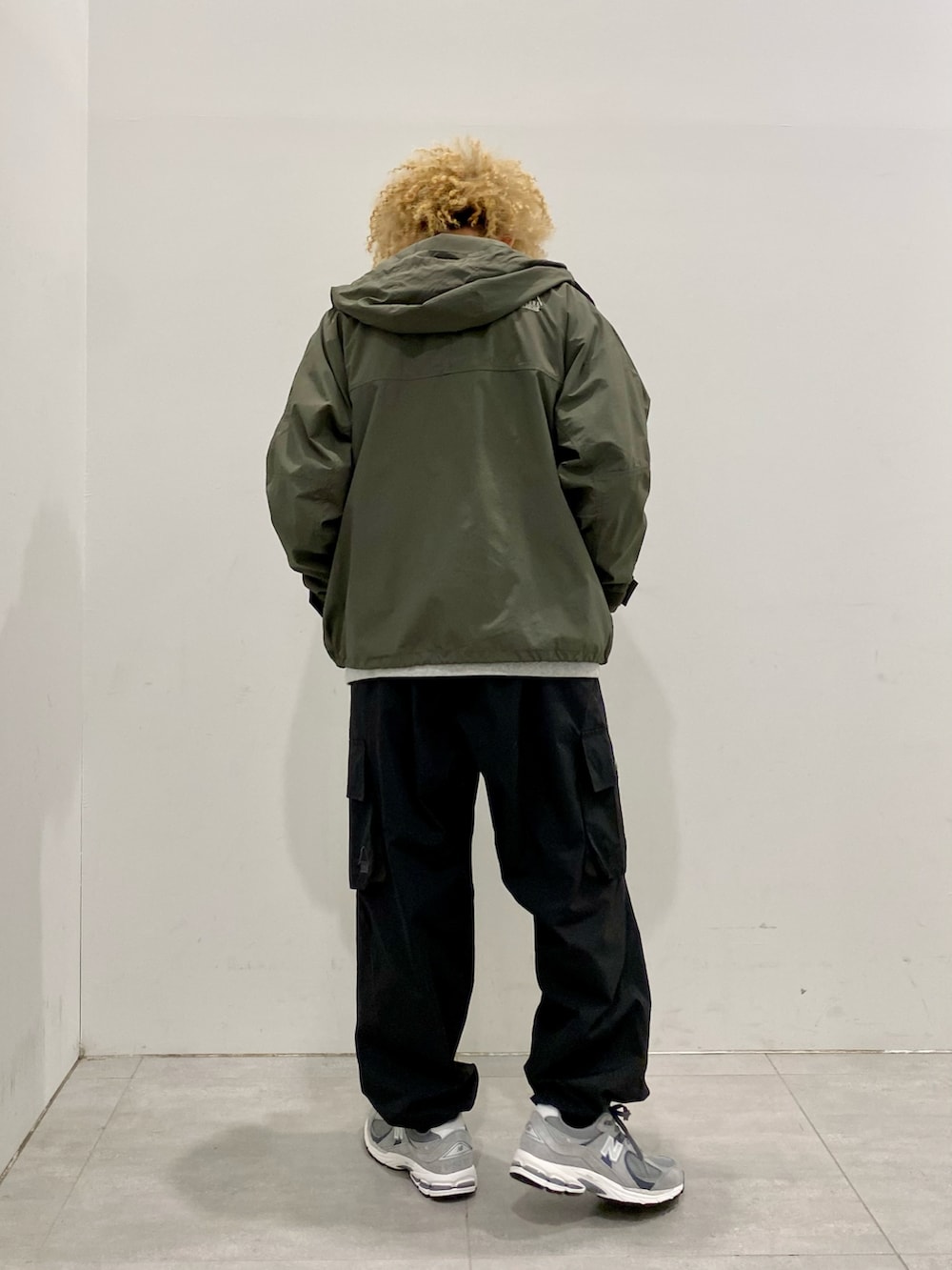 グリーン系のマウンテンパーカー、ブラック系のカーゴパンツ、グレー系のスニーカーを着用したメンズの春コーディネートの2枚目の写真