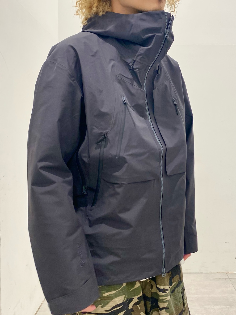 ブラック系のマウンテンパーカー、グレー系のニット/セーター、グリーン系のカーゴパンツを着用したメンズの秋コーディネートの3枚目の写真