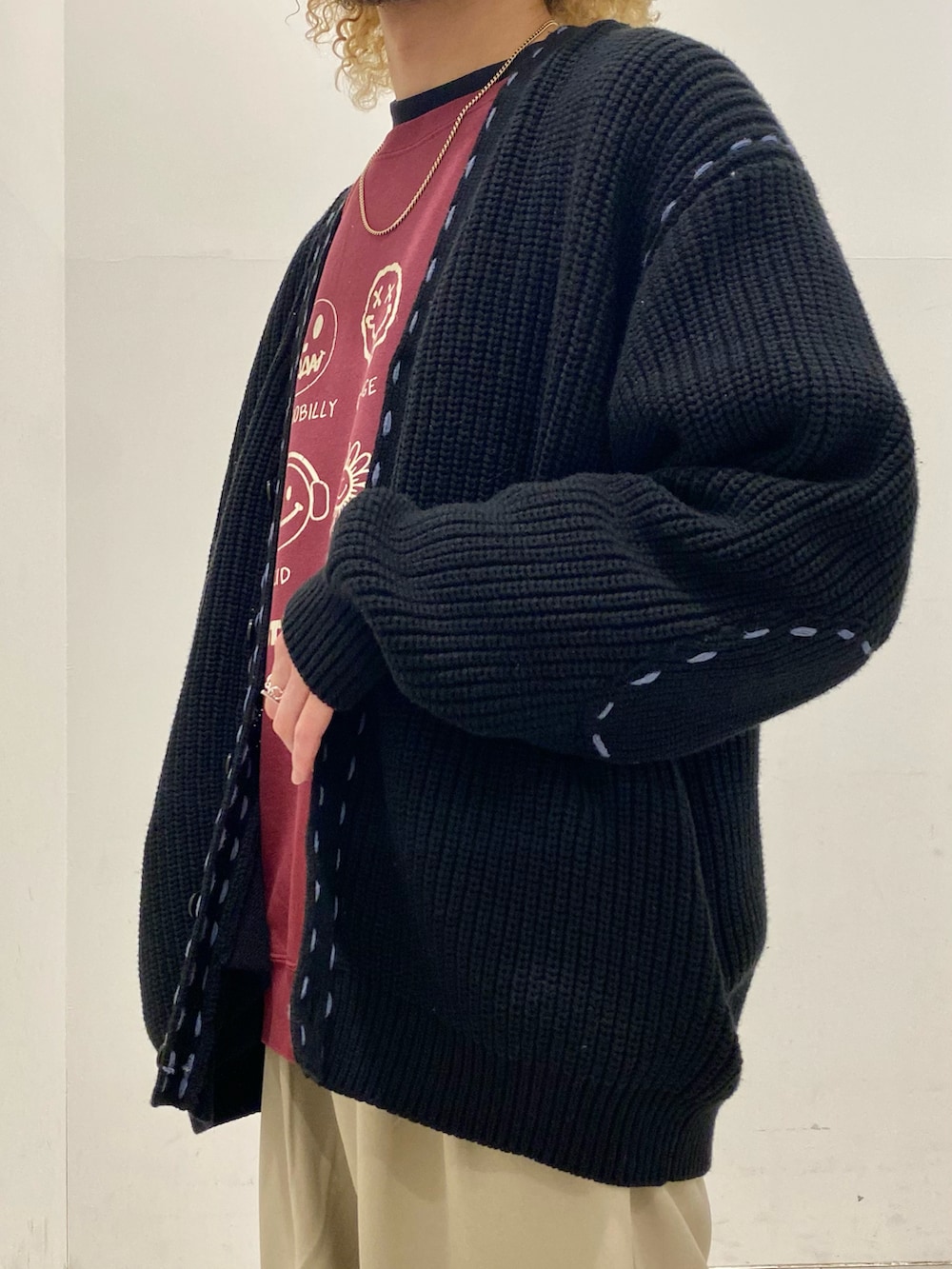 ブラック系のカーディガン/ボレロ、レッド系のスウェット、ベージュ系のスラックスを着用したメンズの秋コーディネートの3枚目の写真