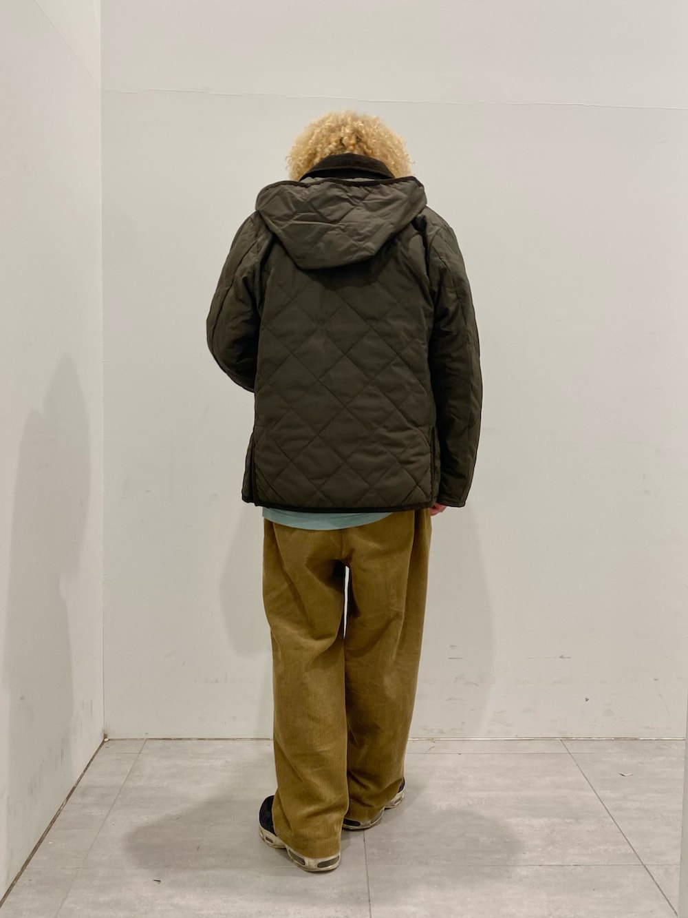 グリーン系のダウンジャケット/コート、イエロー系のニット/セーター、イエロー系のスラックスを着用したメンズの秋コーディネートの2枚目の写真