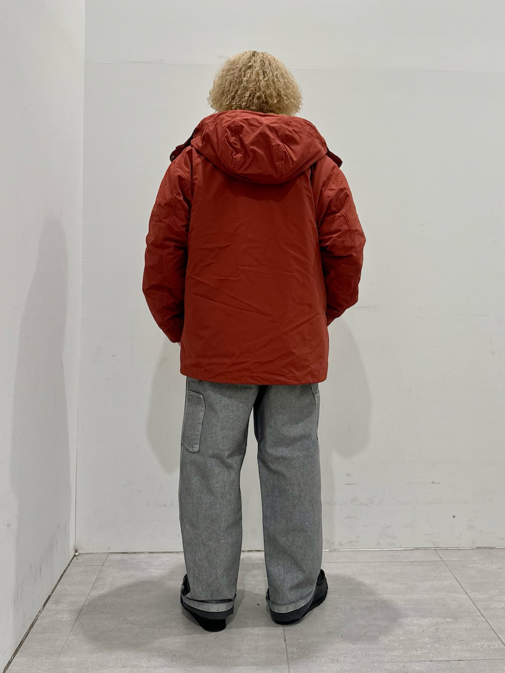 オレンジ系のマウンテンパーカー、グリーン系のニット/セーター、グレー系のパンツを着用したメンズの秋コーディネートの3枚目の写真