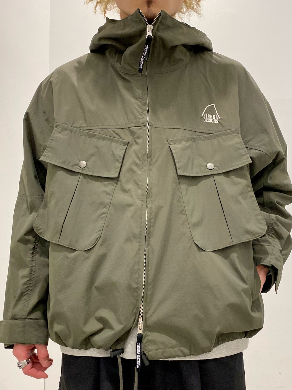 グリーン系のマウンテンパーカー、ブラック系のカーゴパンツ、グレー系のスニーカーを着用したメンズの春コーディネートの3枚目の写真