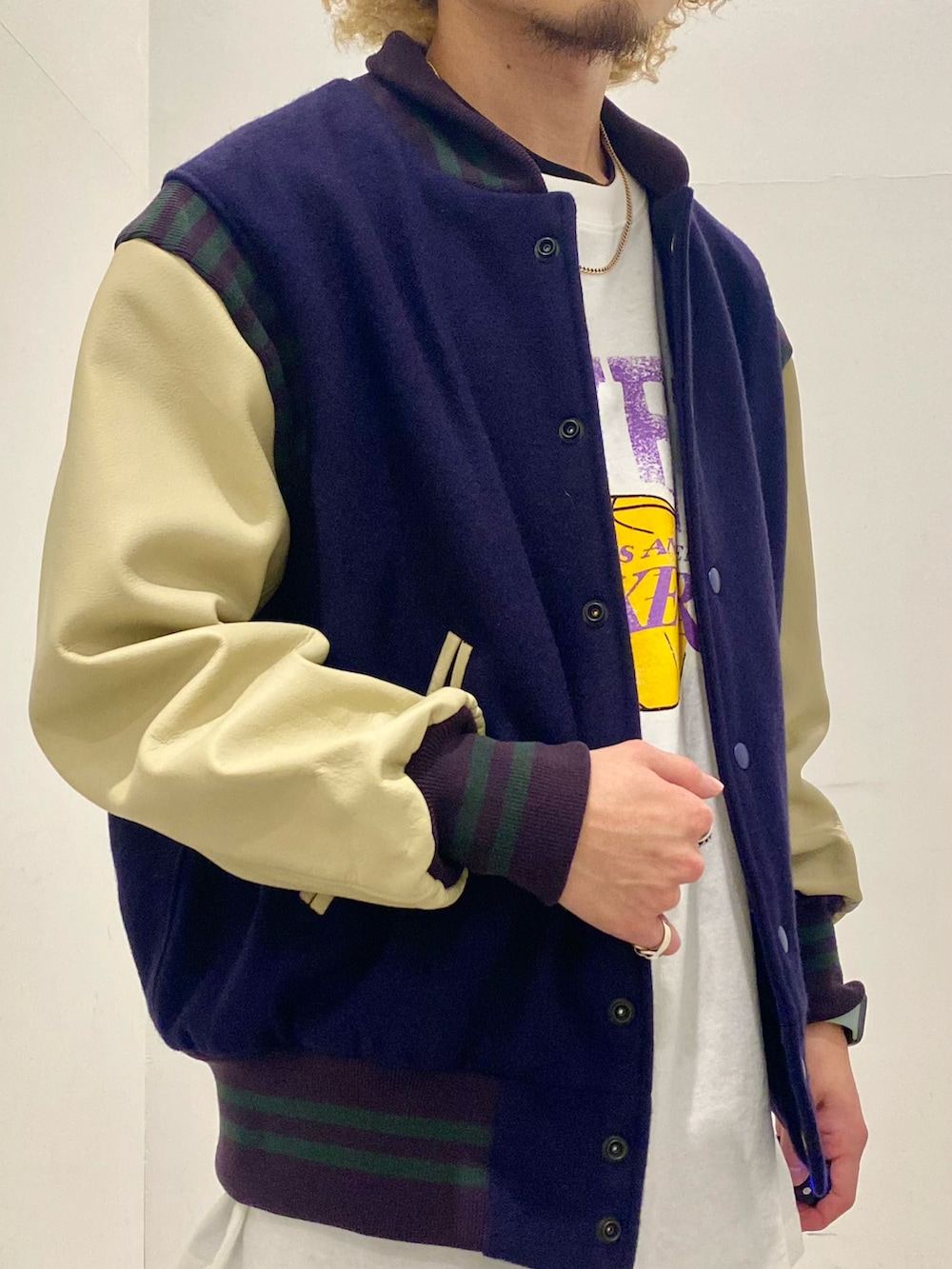 パープル系のスタジャン、グレー系のTシャツ/カットソー、ブルー系のデニムパンツを着用したメンズの秋コーディネートの3枚目の写真