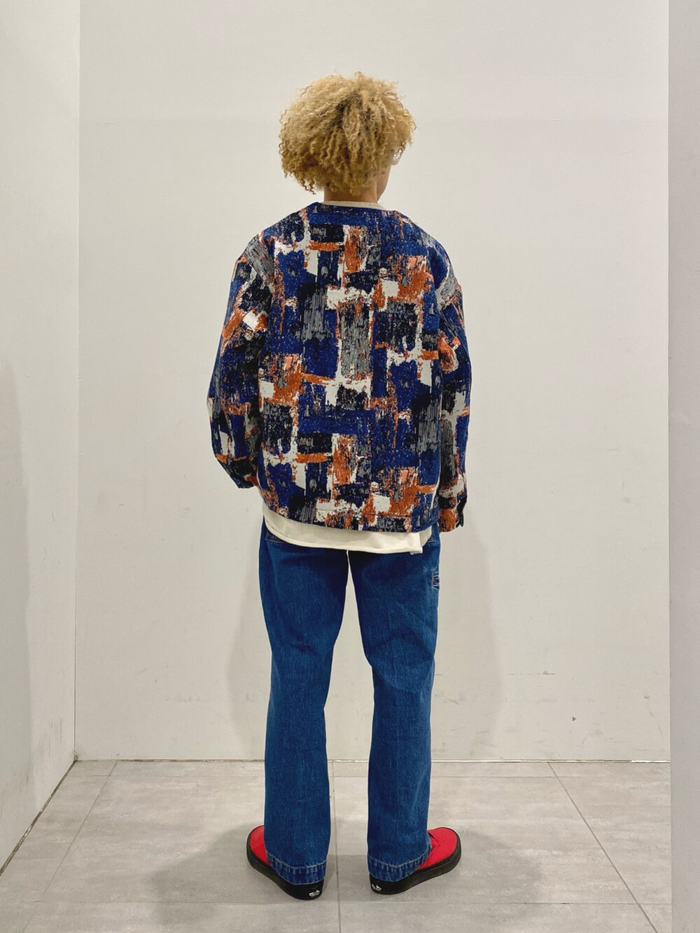 ブルー系のノーカラージャケット、ベージュ系のTシャツ/カットソー、ブルー系のデニムパンツを着用したメンズの冬コーディネートの2枚目の写真