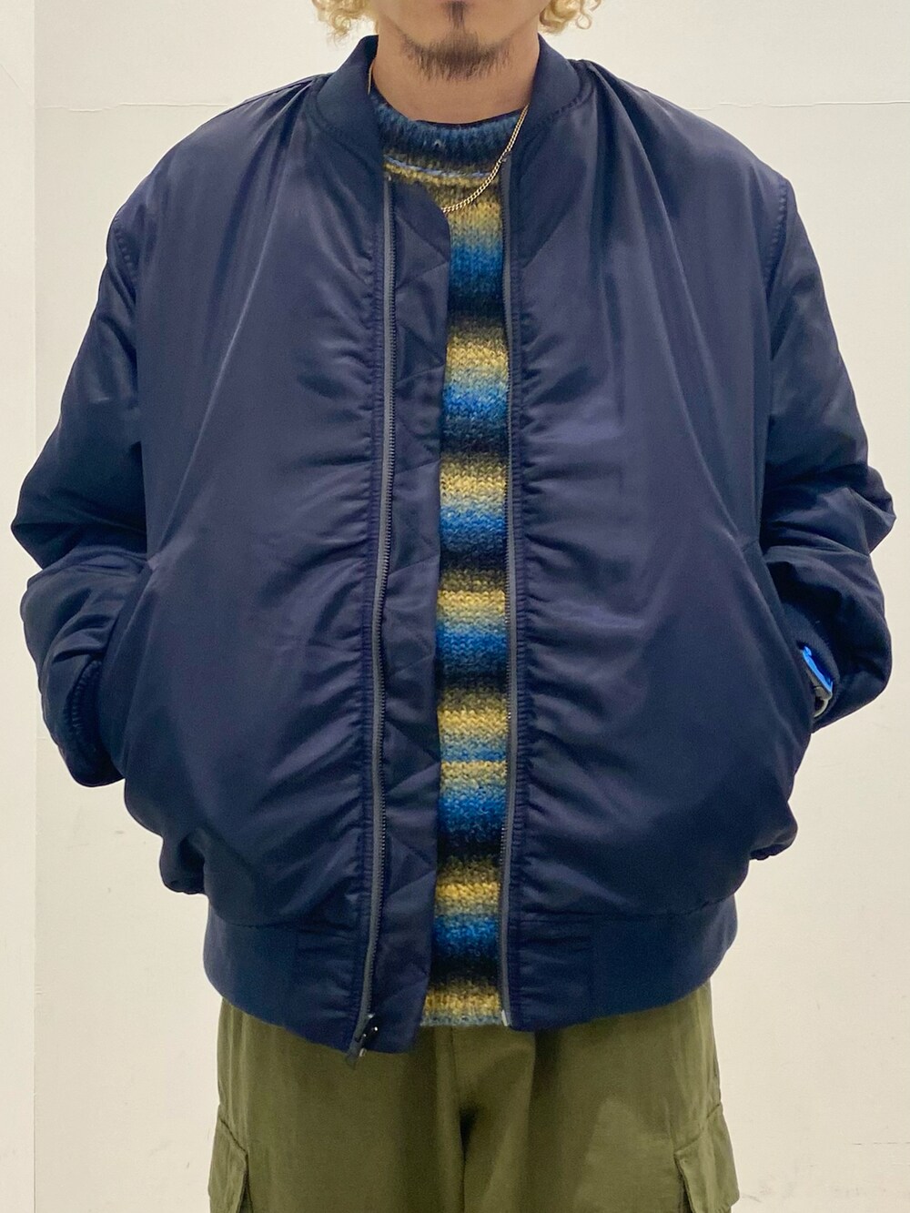 ブルー系のMA-1、ブルー系のニット/セーター、グリーン系のカーゴパンツを着用したメンズの秋コーディネートの3枚目の写真