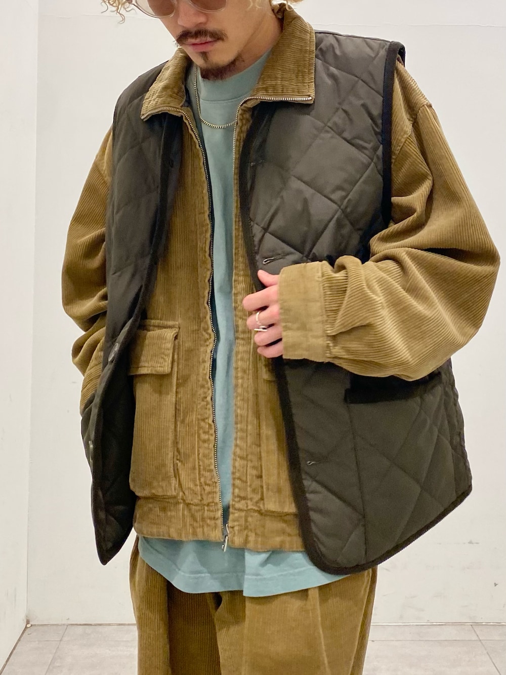 グリーン系のダウンベスト、イエロー系のブルゾン、イエロー系のスラックスを着用したメンズの秋コーディネートの4枚目の写真