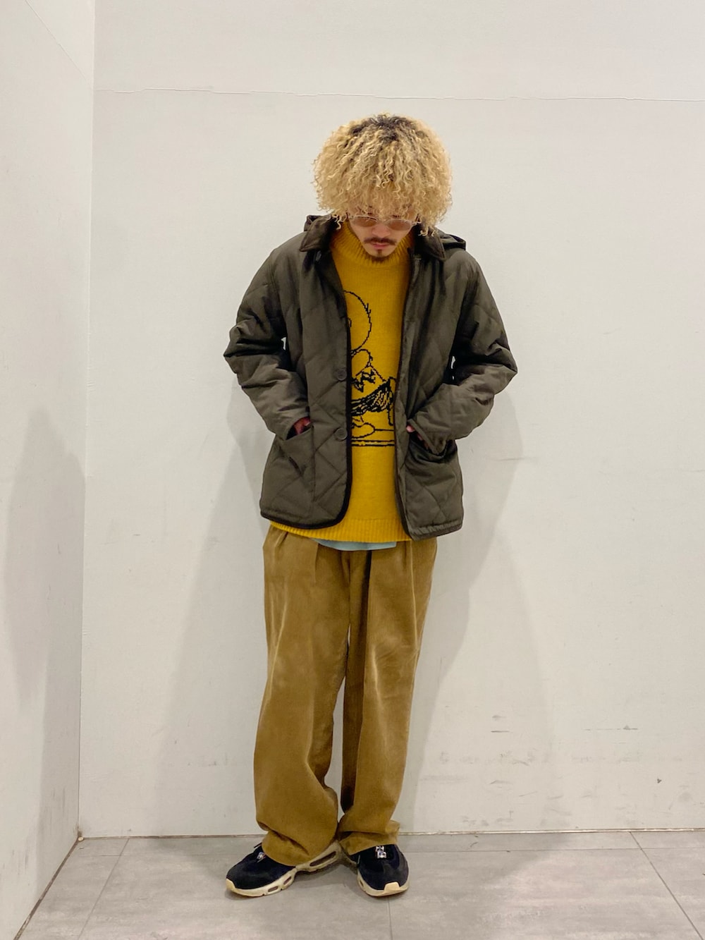 グリーン系のダウンジャケット/コート、イエロー系のニット/セーター、イエロー系のスラックスを着用したメンズの秋コーディネートの3枚目の写真