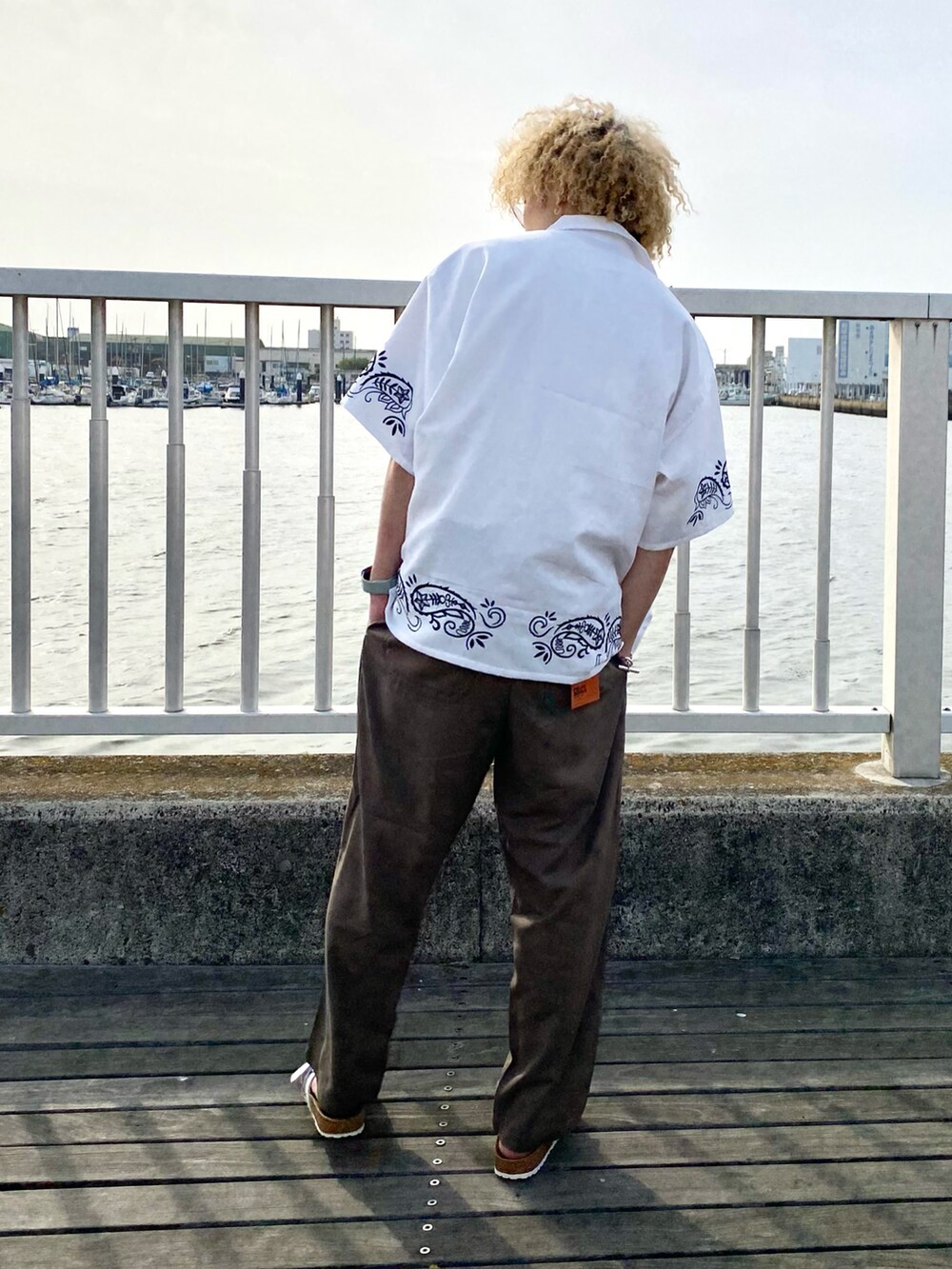 ホワイト系のシャツ/ブラウス、ブラウン系のスラックス、ホワイト系のサンダルを着用したメンズの春コーディネートの2枚目の写真