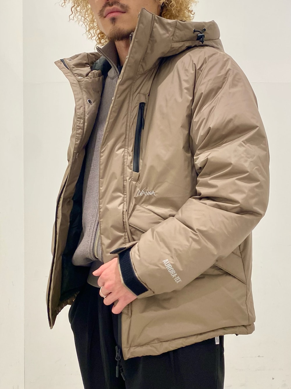 イエロー系のダウンジャケット/コート、グレー系のニット/セーター、ブラック系のスラックスを着用したメンズの秋コーディネートの2枚目の写真