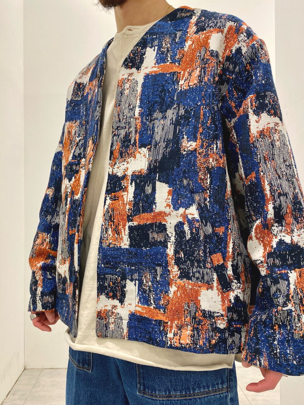 ブルー系のノーカラージャケット、ベージュ系のTシャツ/カットソー、ブルー系のデニムパンツを着用したメンズの冬コーディネートの3枚目の写真