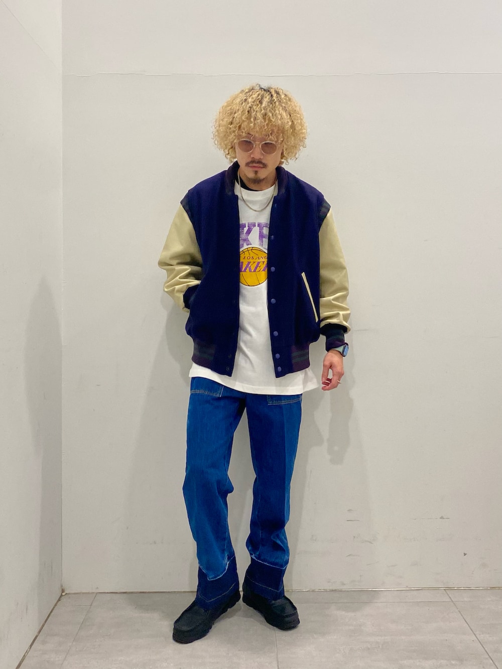 パープル系のスタジャン、グレー系のTシャツ/カットソー、ブルー系のデニムパンツを着用したメンズの秋コーディネートの2枚目の写真