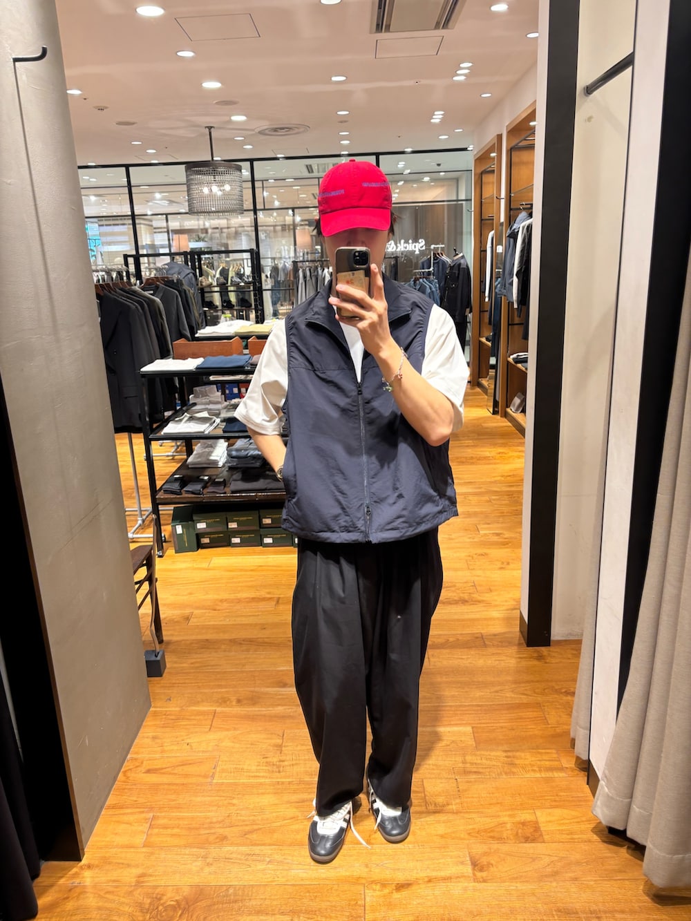 ブルー系のベスト、ブラック系のその他パンツ、レッド系のキャップを着用したメンズの春コーディネートの3枚目の写真