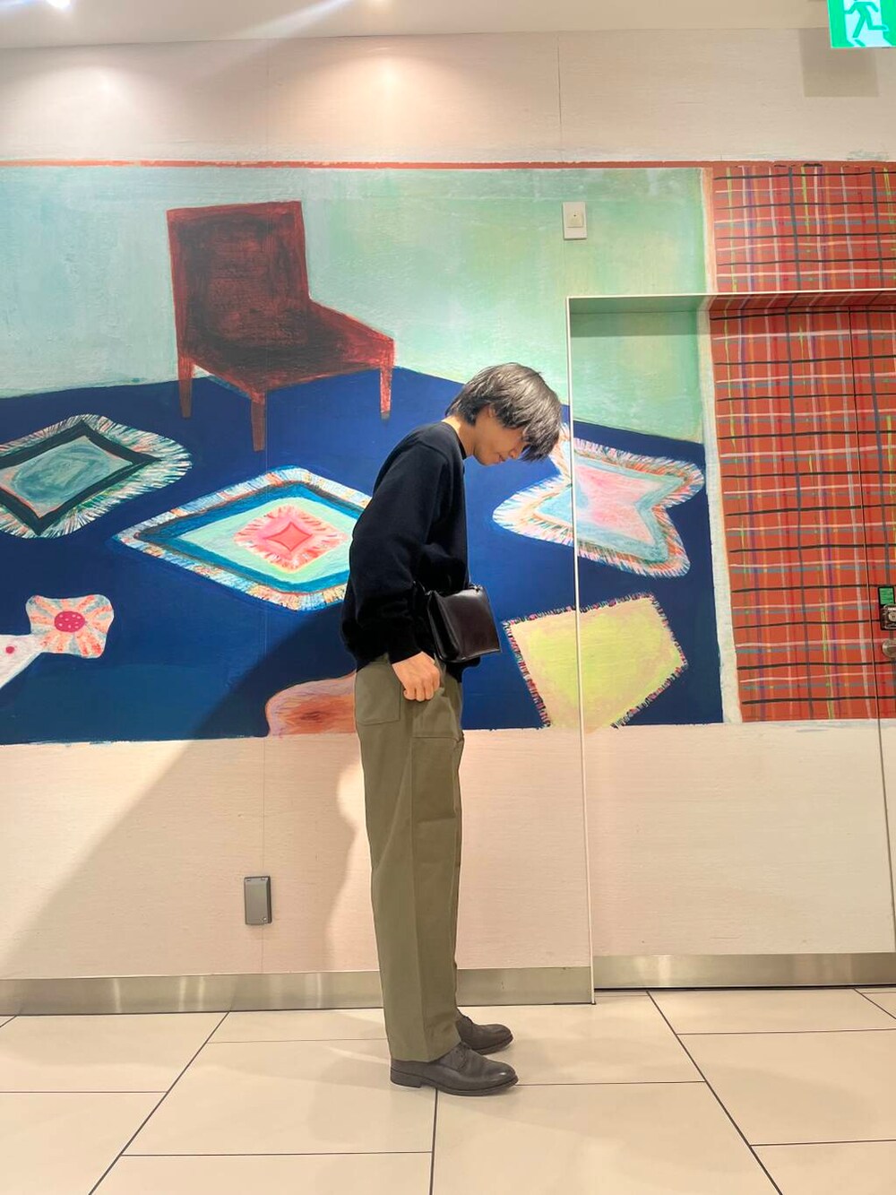 ブラック系のショルダーバッグ、ブラック系のニット/セーター、グリーン系のチノパンツを着用したメンズの夏コーディネートの3枚目の写真