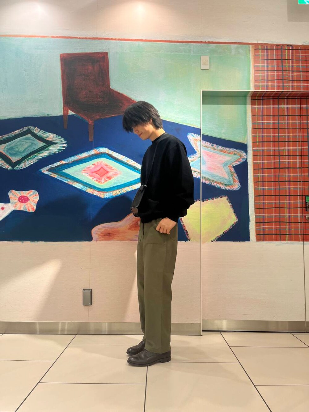 ブラック系のショルダーバッグ、ブラック系のニット/セーター、グリーン系のチノパンツを着用したメンズの夏コーディネートの4枚目の写真