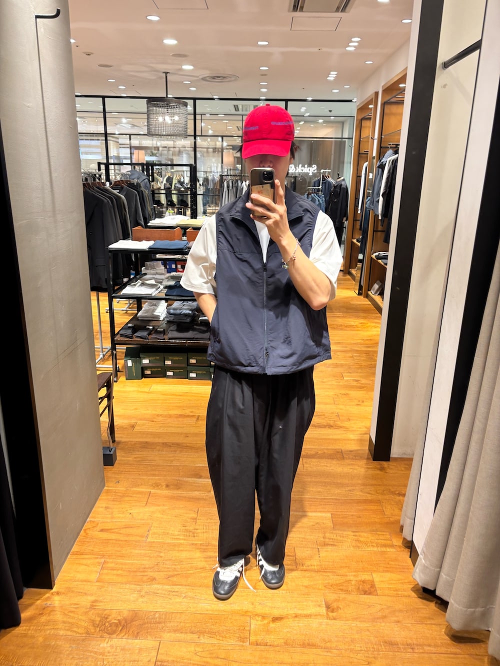 ブルー系のベスト、ブラック系のその他パンツ、レッド系のキャップを着用したメンズの春コーディネートの2枚目の写真