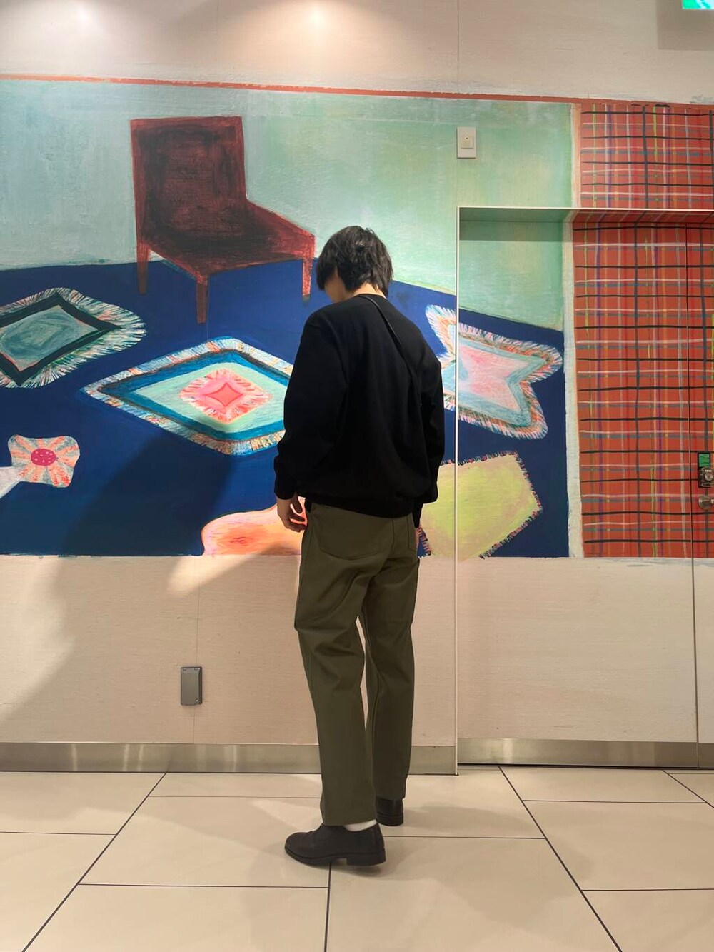 ブラック系のショルダーバッグ、ブラック系のニット/セーター、グリーン系のチノパンツを着用したメンズの夏コーディネートの5枚目の写真