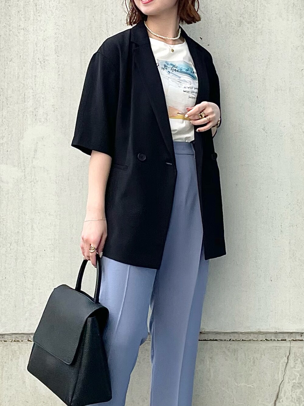ブラック系のスーツジャケット、ホワイト系のTシャツ/カットソー、ブルー系のスーツパンツを着用したレディースの春コーディネートの4枚目の写真