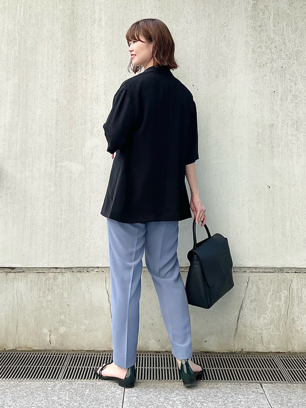 ブラック系のスーツジャケット、ホワイト系のTシャツ/カットソー、ブルー系のスーツパンツを着用したレディースの春コーディネートの3枚目の写真