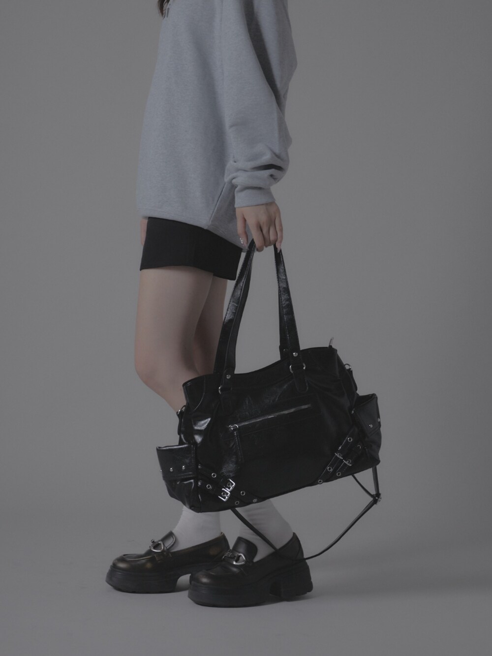 グレー系のスウェット、ブラック系のショルダーバッグを着用したレディースの秋コーディネートの2枚目の写真