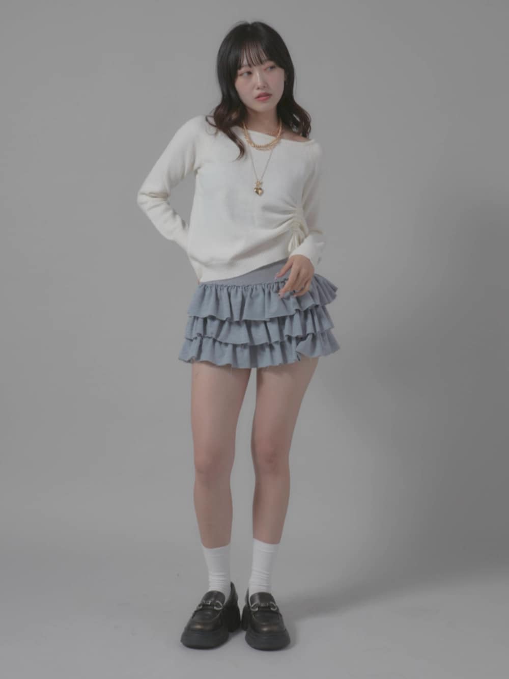 グレー系のスカート、ホワイト系のニット/セーターを着用したレディースの秋コーディネートの2枚目の写真