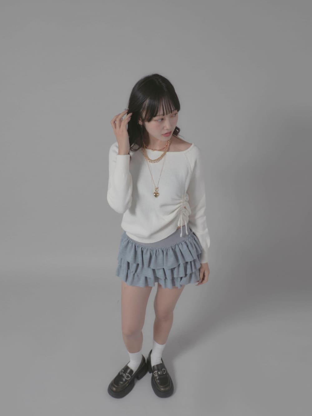 グレー系のスカート、ホワイト系のニット/セーターを着用したレディースの秋コーディネートの3枚目の写真