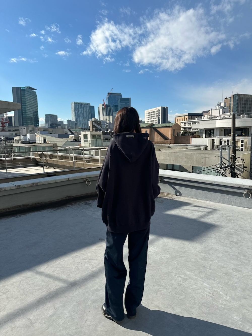 ブルー系のパーカー、ブルー系のチノパンツ、ブラウン系のパーカーを着用したレディースの春コーディネートの3枚目の写真