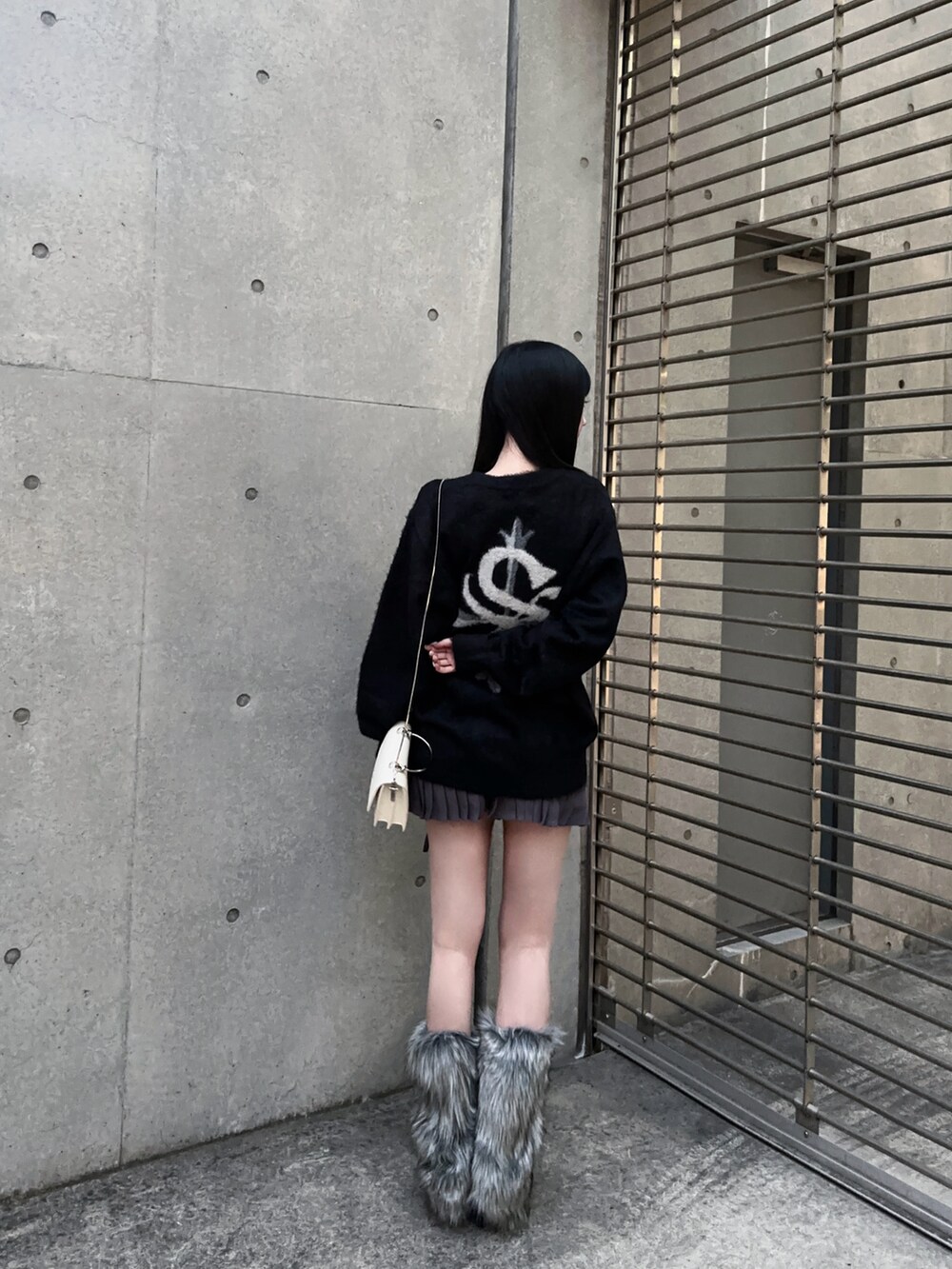 グレー系のスカート、ブラック系のニット/セーター、グレー系のレッグウォーマーを着用したレディースの秋コーディネートの2枚目の写真
