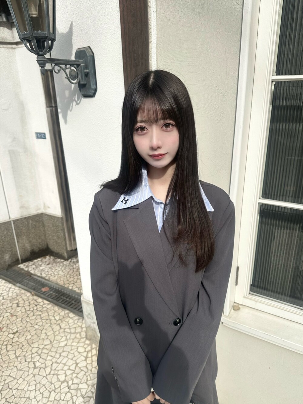 グレー系のテーラードジャケット、グレー系のスカート、ブラック系のショルダーバッグを着用したレディースの冬コーディネートの2枚目の写真