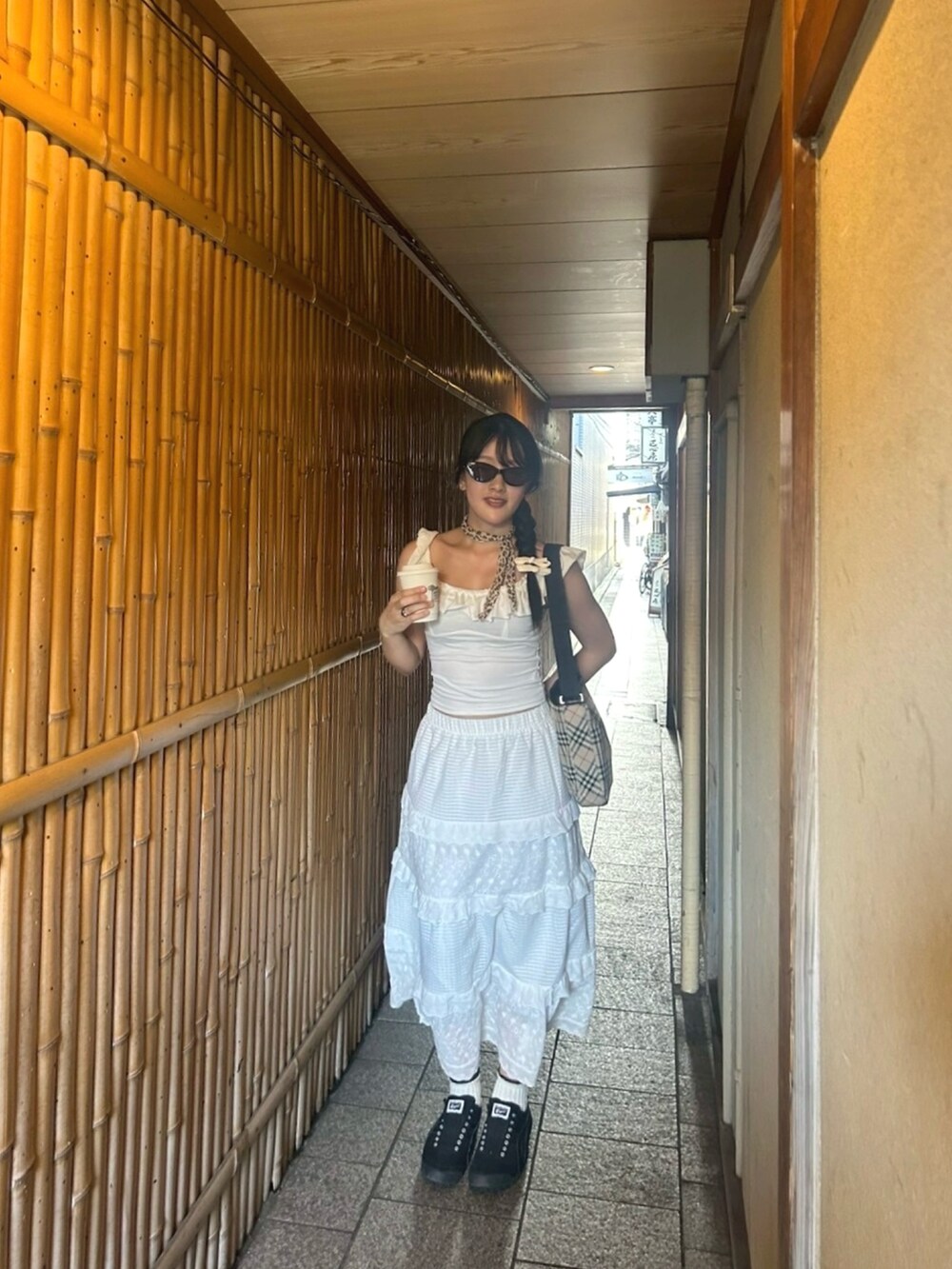 ホワイト系のスカート、ブラック系のスニーカー、ベージュ系のショルダーバッグを着用したレディースの夏コーディネートの2枚目の写真