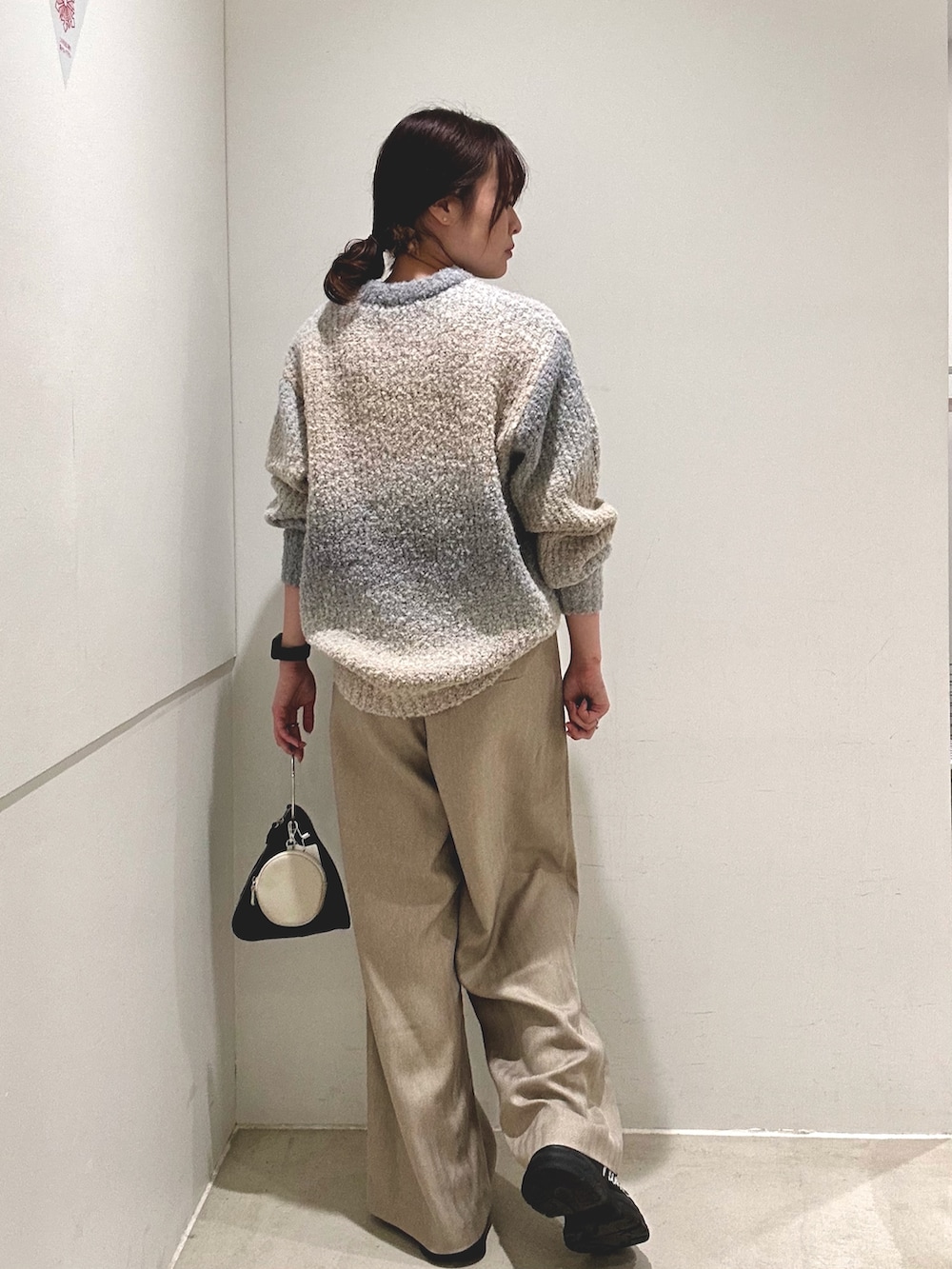 グレー系のニット/セーター、ベージュ系のその他パンツ、ブラック系のハンドバッグを着用したレディースの秋コーディネートの3枚目の写真