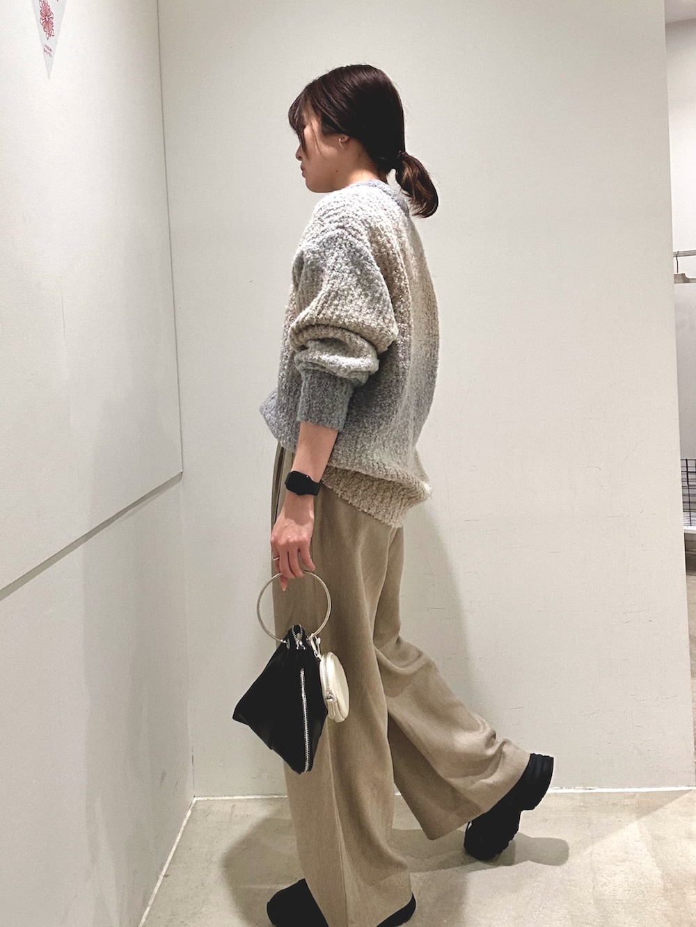 グレー系のニット/セーター、ベージュ系のその他パンツ、ブラック系のハンドバッグを着用したレディースの秋コーディネートの2枚目の写真