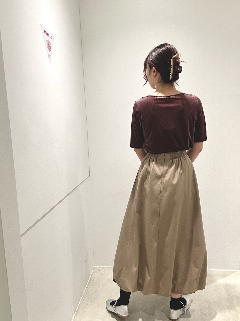 レッド系のTシャツ/カットソー、ベージュ系のスカート、ブラウン系のハンドバッグを着用したレディースの秋コーディネートの3枚目の写真