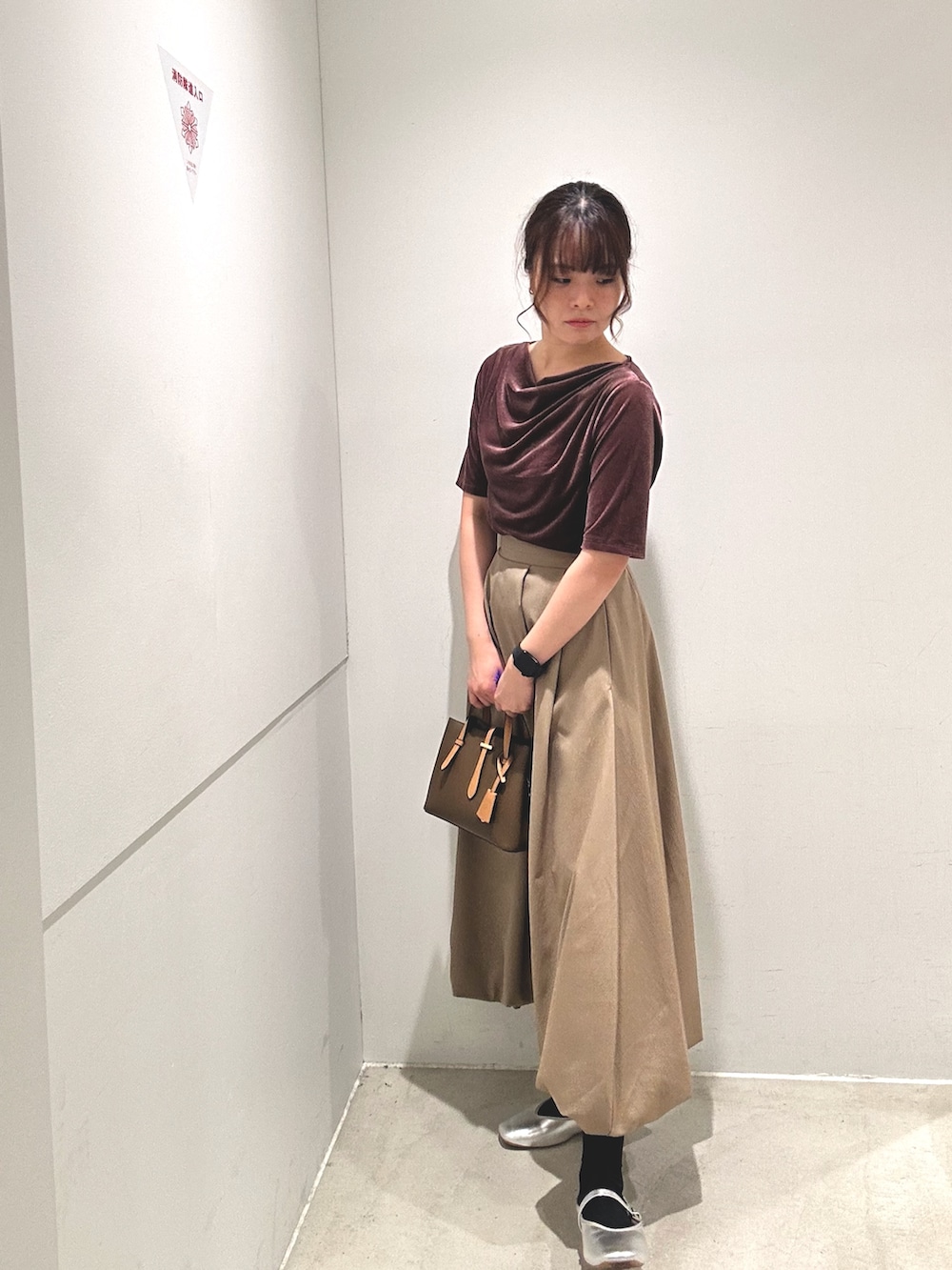 レッド系のTシャツ/カットソー、ベージュ系のスカート、ブラウン系のハンドバッグを着用したレディースの秋コーディネートの4枚目の写真