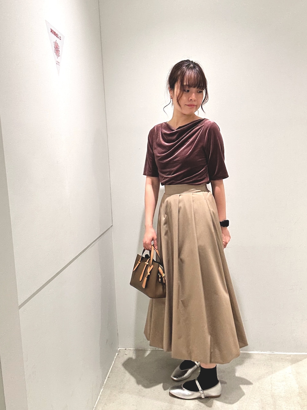 レッド系のTシャツ/カットソー、ベージュ系のスカート、ブラウン系のハンドバッグを着用したレディースの秋コーディネートの2枚目の写真