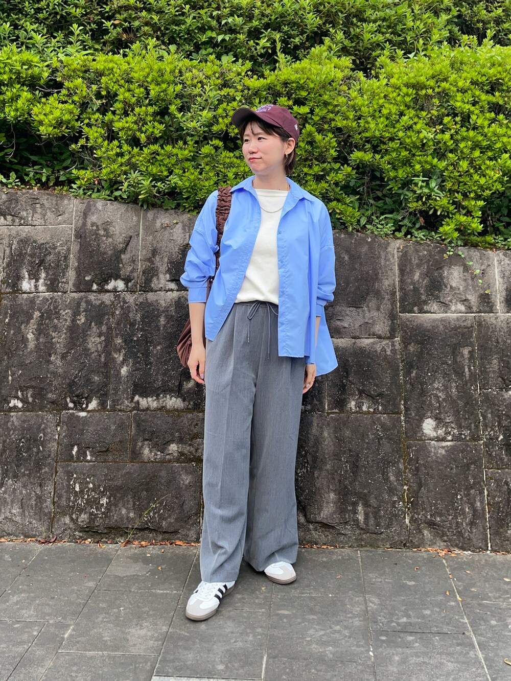 ホワイト系のTシャツ/カットソー、ブラウン系のショルダーバッグ、ホワイト系のスニーカーを着用したレディースの秋コーディネートの2枚目の写真