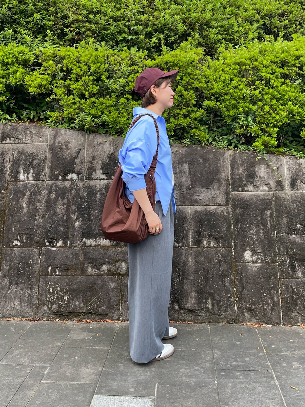 ホワイト系のTシャツ/カットソー、ブラウン系のショルダーバッグ、ホワイト系のスニーカーを着用したレディースの秋コーディネートの3枚目の写真